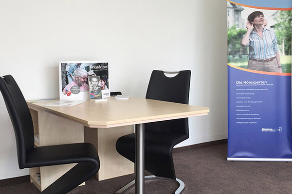 Moderner Beratungsplatz für Hörgeräte mit Informationsmaterial und Werbebanner im Büro.